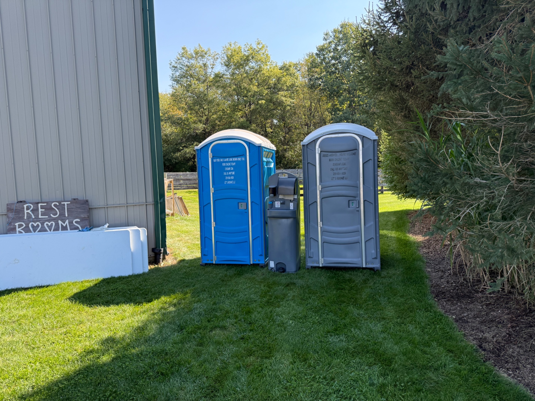 Blue Let's Go Potty Rentals porta potty and gray handwash station set up beside a barn for an outdoor wedding on a farm near Fair Oaks, Indiana